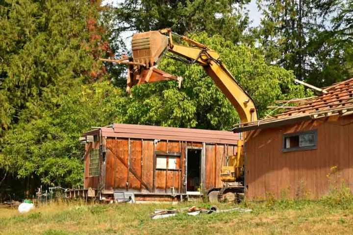 Excavator destroying old house demolition