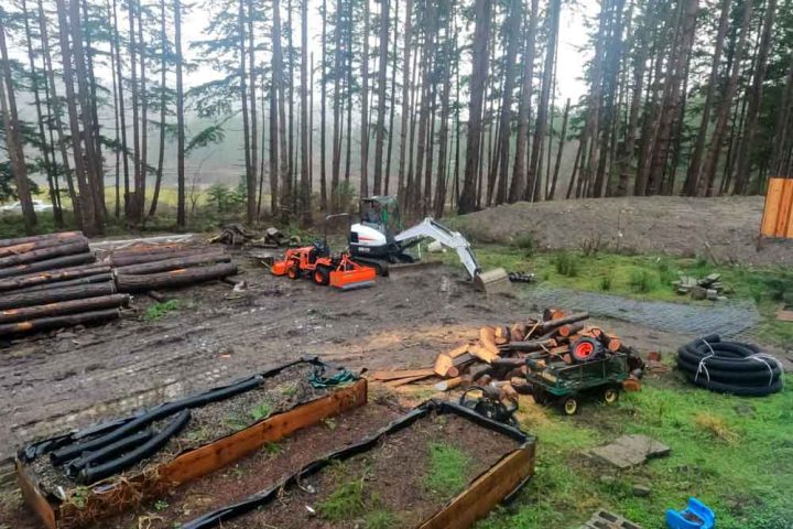 work area in the woods, cut logs, mini-excavator and drain pipes