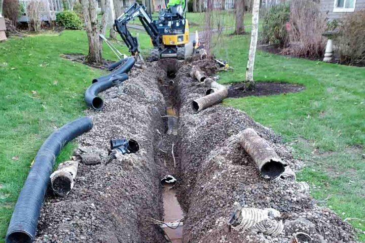 a mini excavator digging a ditch in a house yard, replacing old drainage pipes